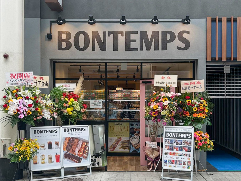 BONTEMPS熊本上通店の店舗外観。オープン祝いの花とドーナツやドリンクの看板が並ぶ、モダンでカラフルな店構え